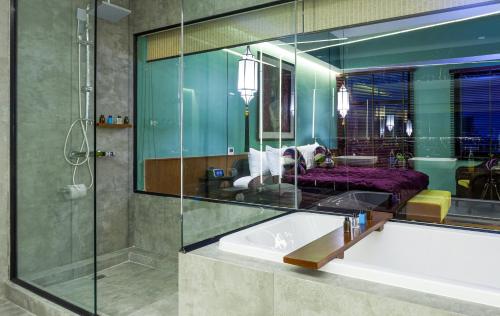 La salle de bains est pourvue d'une baignoire et d'une douche en verre. dans l'établissement Lao Poet Hotel, à Vientiane