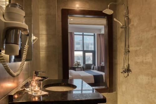 Un baño con lavabo y espejo y un dormitorio. en Torino Hotel Amman, en Amán