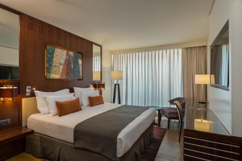 a hotel room with a large bed and a desk at King Solomon by Isrotel Collection in Eilat
