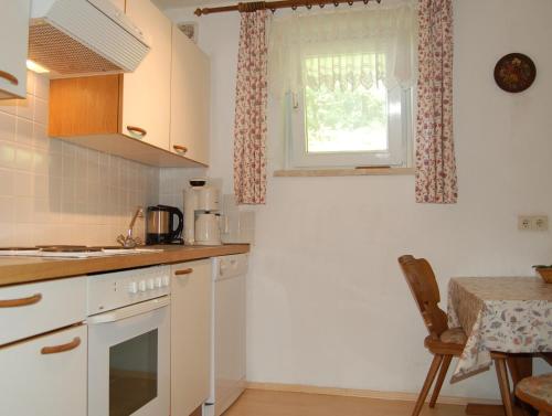 cocina con armarios blancos, mesa y ventana en Ferienwohungen Wassertheurer, en Sankt Kanzian