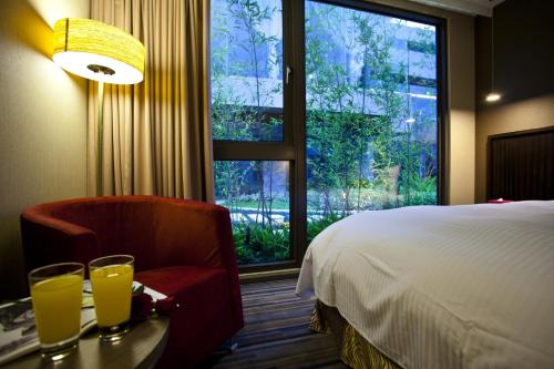 a hotel room with a bed and a chair and a window at In Sky Hotel in Taichung