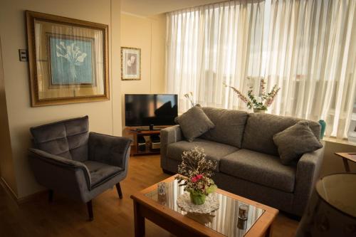 sala de estar con sofá y silla en Departamentos Los Ganaderos, en Punta Arenas