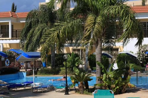 a beach with palm trees and palm trees at Jacaranda Hotel Apartments in Protaras