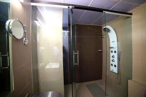 a shower with a glass door in a bathroom at Hotel Rajdoot Royale by Ambai in Ichalkaranji