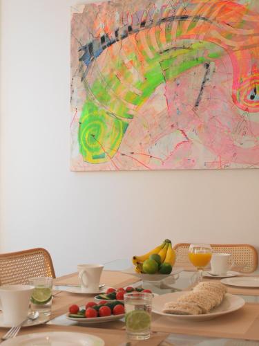 a table with plates of fruit and a painting on the wall at Miró Studio Apartments Dubrovnik in Dubrovnik