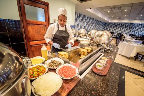 een chef-kok die maaltijden bereidt in een restaurantkeuken bij Birchwood Hotel and OR Tambo Conference Centre in Boksburg