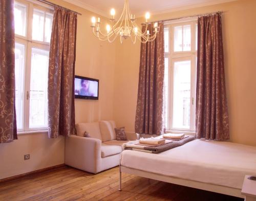 a bedroom with a bed and a couch and windows at Hello Sofia Guesthouse in Sofia