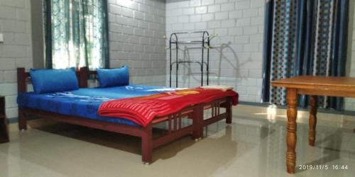 a bedroom with a bed with blue sheets and a table at Periyar Green Bed & Breakfast in Thekkady