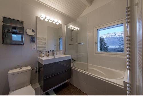 uma casa de banho com um WC, um lavatório e uma janela em Unique Chalet avec vue a 360 degres - LLA Selections by Location Lac Annecy em Doussard