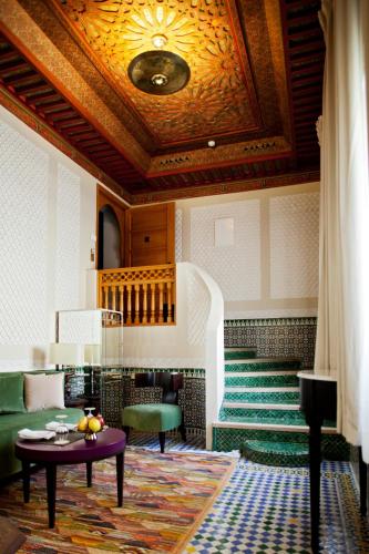 a living room with a table and green chairs at Palais Faraj Suites & Spa in Fès
