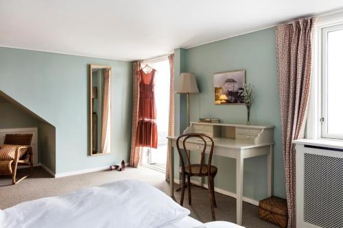 a bedroom with a bed and a desk and a chair at Helenekilde Badehotel in Tisvildeleje