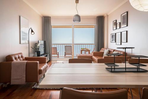 a living room with leather furniture and a view of the ocean at Reis Magos III by An Island Apart in Caniço