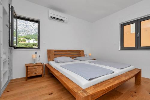 a bedroom with a large bed and two windows at Luxury apartment Macola Free beach parking in Makarska