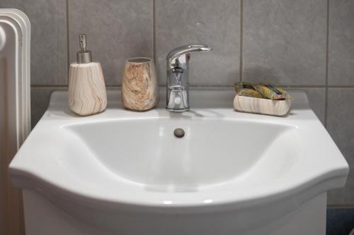 a bathroom sink with a faucet and two containers on it at Cozy Studio in Trikala Center with private Parking! in Tríkala
