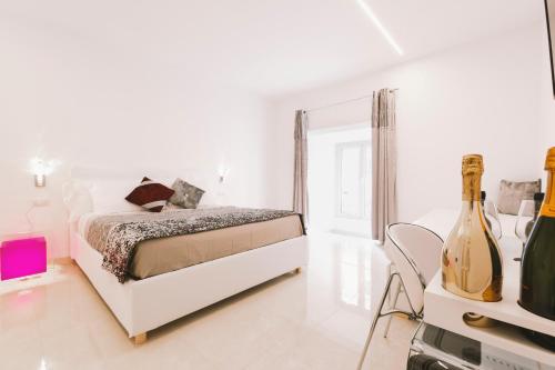 a white bedroom with a bed and a bottle of wine at San Pietro Grand Suite in Rome