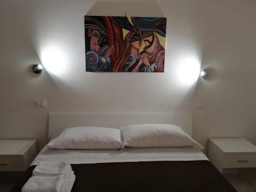a bedroom with a bed with a painting on the wall at Opera Boutique Rooms in Monreale