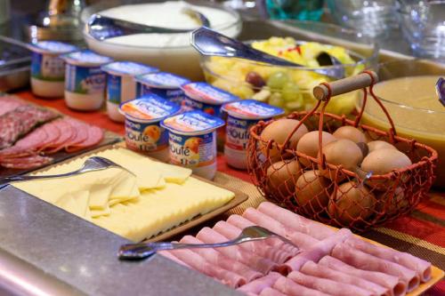 a table topped with cheese and meats and other foods at FH Confort Hotel Orléans Co'met in Orléans
