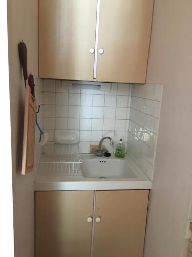 Il comprend une cuisine avec un évier et un mur carrelé blanc. dans l'établissement Au pieds des 3 vallées, à Brides-les-Bains