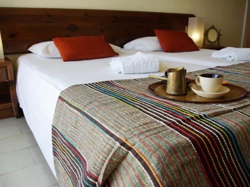 two beds in a hotel room with a tray with a cup of coffee at Thomas Hotel in Monólithos