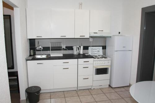a kitchen with white cabinets and a white refrigerator at Apartman Zen in Osijek