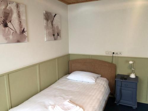 a small bedroom with a bed and a night stand at Hotel Verhoeven in Uden
