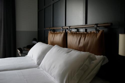 un letto con lenzuola e cuscini bianchi in una stanza di c-hotels Club House Roma a Roma