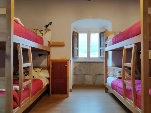 two bunk beds in a room with a window at La Figal de Xugabolos, Salas in Salas