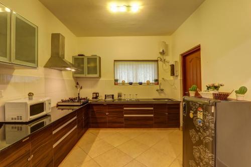 une cuisine avec un réfrigérateur et un micro-ondes dans l'établissement Heritage Exotica Villa - 4BHK, Baga, à Baga
