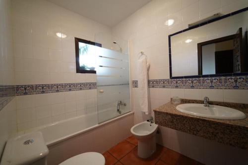 a bathroom with a sink and a toilet and a mirror at Hostal LA DEHESA DEL VALLE PEDROCHES in Alcaracejos