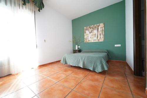 a room with a bed and a green wall at Hostal LA DEHESA DEL VALLE PEDROCHES in Alcaracejos