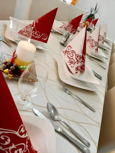 a table with white plates and red napkins and a candle at Jolán Pension & Restaurant in Číčov