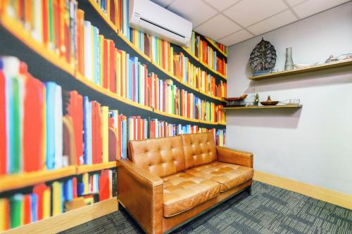 a leather chair in front of a wall of books at Stewart by Heeton Concept - Aparthotel Edinburgh in Edinburgh