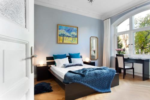 a bedroom with blue walls and a bed with a desk at Elite Apartments Sopot Admiralski przy plaży in Sopot