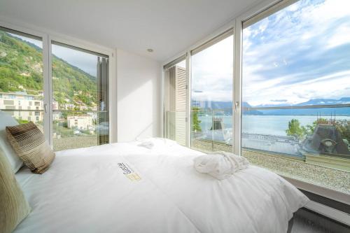 a bedroom with a white bed and a large window at Luxury Apartment Lake View & Center of Montreux by GuestLee in Montreux