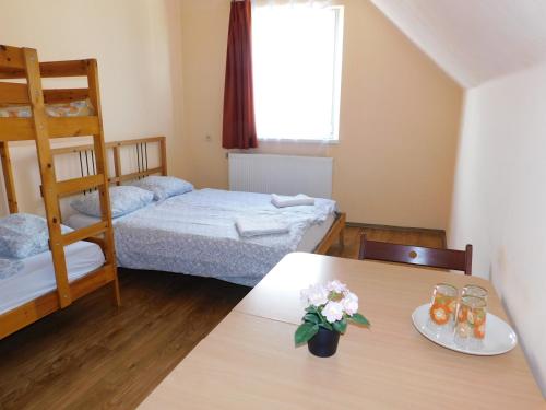 ein Zimmer mit 2 Etagenbetten und einem Tisch mit Blumen darauf in der Unterkunft Börzsöny Kapuja Vendégház in Zebegény