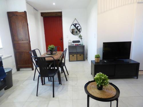 un salon avec une table, des chaises et une télévision dans l'établissement La tourelle 82, à Saint-Antonin