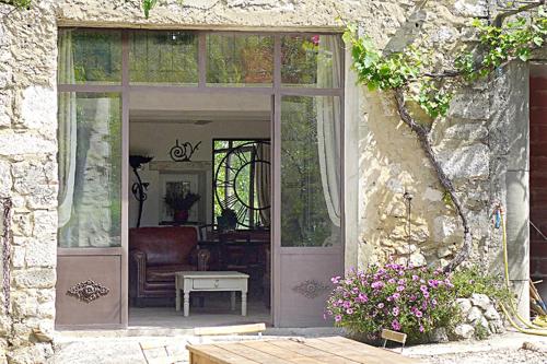 - une porte menant à une terrasse avec une chaise et une table dans l'établissement Les Rochettes, à La Garde-Adhémar