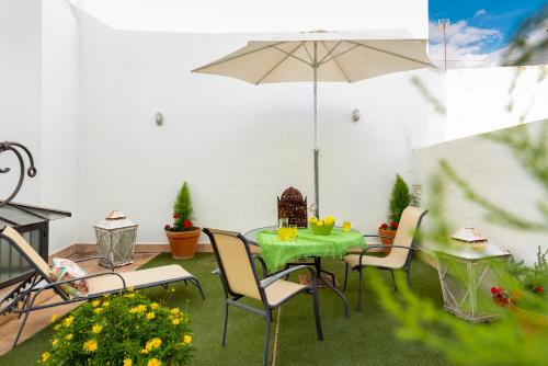 un patio con mesa, sillas y sombrilla en HSH Select Casa Pilatos, en Sevilla