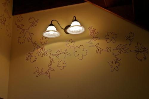 two lights on a wall with flowers on it at Casa Villamana in Oto