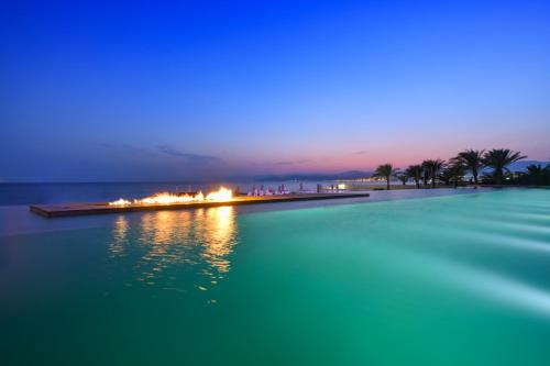 a swimming pool in the middle of the water at night at Kempinski Hotel Aqaba in Aqaba