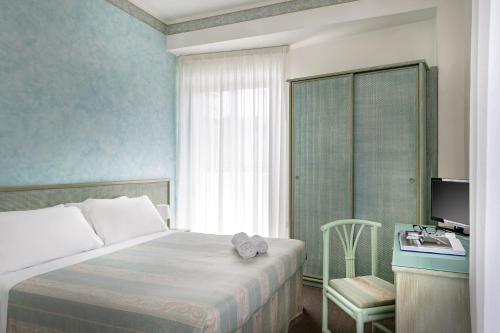 a bedroom with a bed and a desk and a television at Hotel Cristina Corona in Cattolica