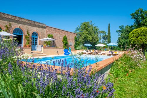 une piscine dans un jardin avec des fleurs violettes dans l'établissement Escudes, à Vigueron