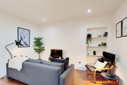 a living room with a gray couch and chairs at WelcomeStay Tooting Broadway 3 Bedroom Apartment in London