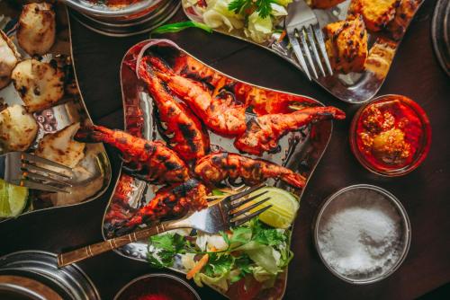 a table topped with plates of food with lobsters and salad at Swahili Beach in Diani Beach