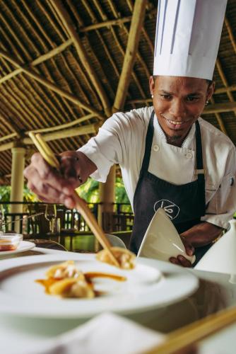 a chef preparing a plate of food on a table at Swahili Beach in Diani Beach