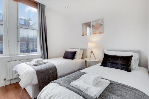 - 2 lits dans une chambre avec fenêtre dans l'établissement WelcomeStay Tooting Broadway 3 Bedroom Apartment, à Londres
