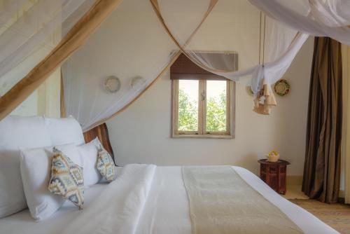 a bedroom with a white bed with a window at Swahili Beach in Diani Beach