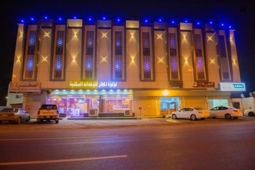 a building with cars parked in front of it at night at Loluat Al Matar Furnished Units in Jazan