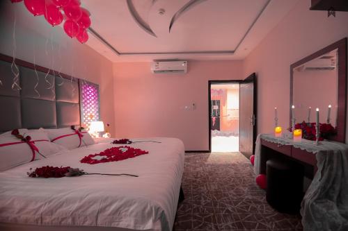 a bedroom with a large bed with red flowers on it at Loluat Al Matar Furnished Units in Jazan