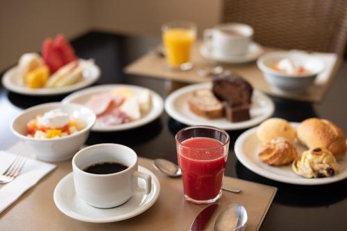a table with plates of breakfast foods and a cup of coffee at Manhattan Plaza in Brasilia
